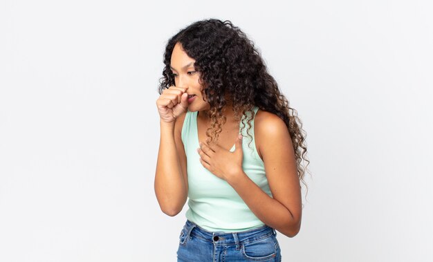 Foto bonita mujer hispana que se siente enferma con dolor de garganta y síntomas de gripe, tos con la boca cubierta