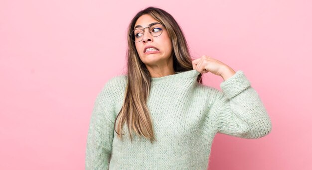 Bonita mujer hispana que se siente estresada, ansiosa, cansada y frustrada tirando del cuello de la camisa luciendo frustrada con el problema