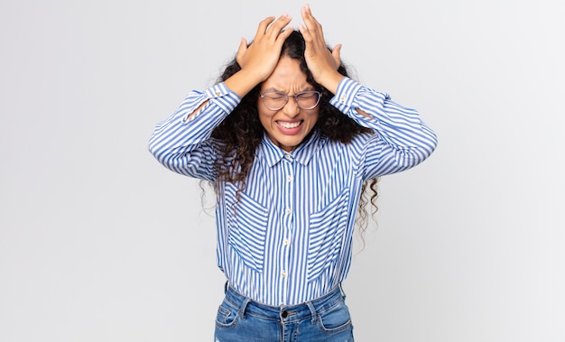 Foto bonita mujer hispana que se siente estresada y ansiosa, deprimida y frustrada con dolor de cabeza, levantando ambas manos a la cabeza