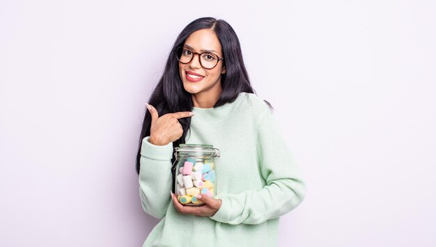 Bonita mujer hispana que se siente feliz y apunta a sí misma con un concepto emocionado de caramelos de gelatina