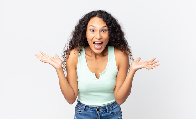 Bonita mujer hispana que se siente feliz, emocionada, sorprendida o conmocionada, sonriendo y asombrada por algo increíble