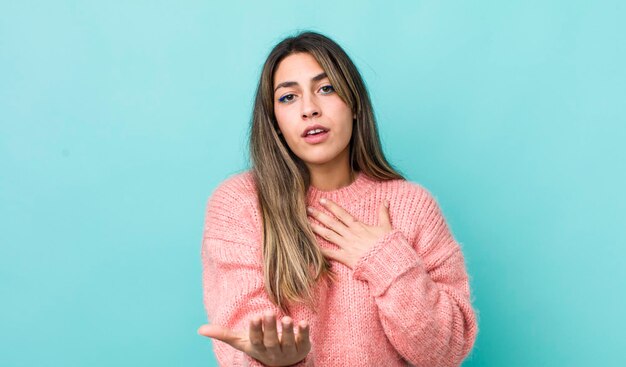 Bonita mujer hispana que se siente feliz y enamorada sonriendo con una mano al lado del corazón y la otra estirada al frente