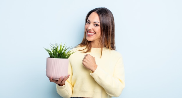 Bonita mujer hispana que se siente feliz y enfrenta un desafío o celebrando. concepto de planta de interior