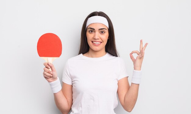 Bonita mujer hispana que se siente feliz mostrando aprobación con el concepto de ping pong de gesto bien