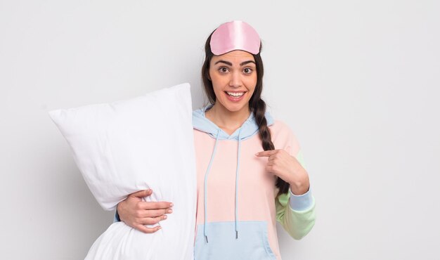 bonita mujer hispana que se siente feliz y se señala a sí misma con entusiasmo. concepto de pijama y almohada