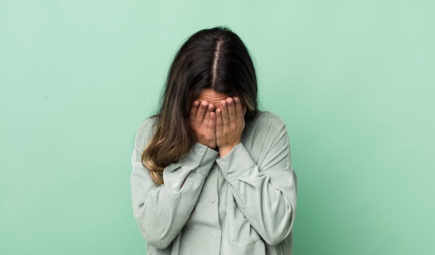 Foto bonita mujer hispana que se siente triste, frustrada, nerviosa y deprimida, cubriéndose la cara con ambas manos llorando