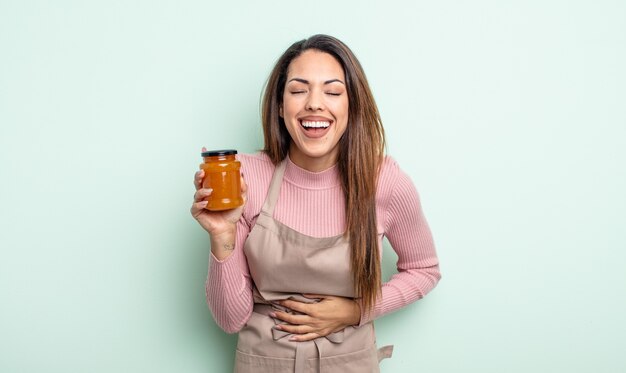 Bonita mujer hispana riéndose a carcajadas de una broma hilarante. concepto de mermelada de durazno