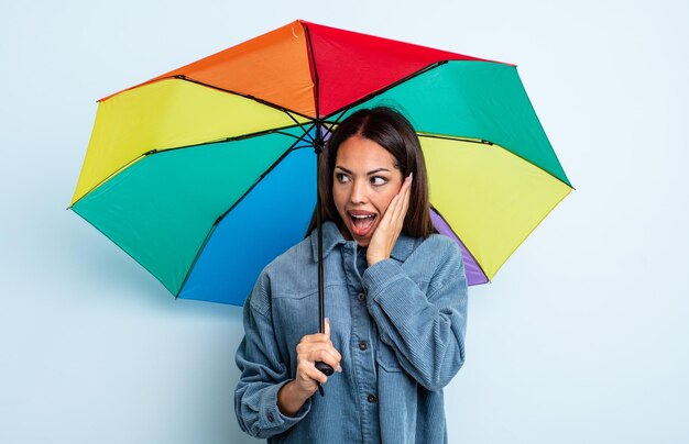 Bonita mujer hispana sintiéndose feliz emocionada y sorprendida concepto de paraguas