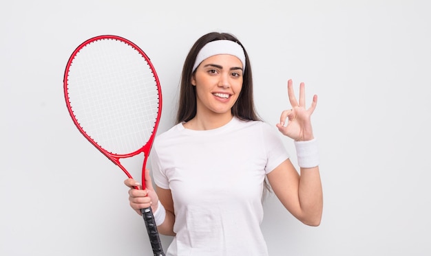 Bonita mujer hispana sintiéndose feliz mostrando aprobación con el concepto de tenis de gesto bien