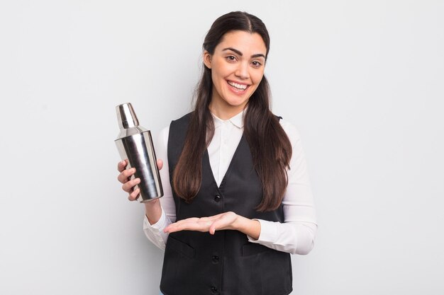 Bonita mujer hispana sonriendo alegremente sintiéndose feliz y mostrando un concepto de cóctel de barman