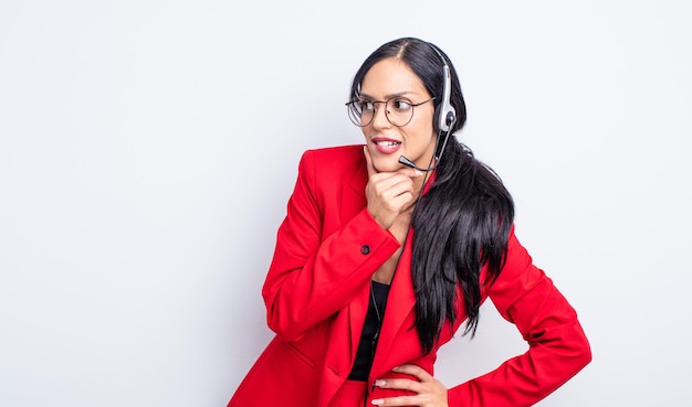 Bonita mujer hispana sonriendo con una expresión feliz y segura con la mano en la barbilla. concepto de telemarketing