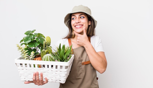 Foto bonita mujer hispana sonriendo con una feliz expresión de confianza con la mano en las plantas de la barbilla y el concepto de jardinería