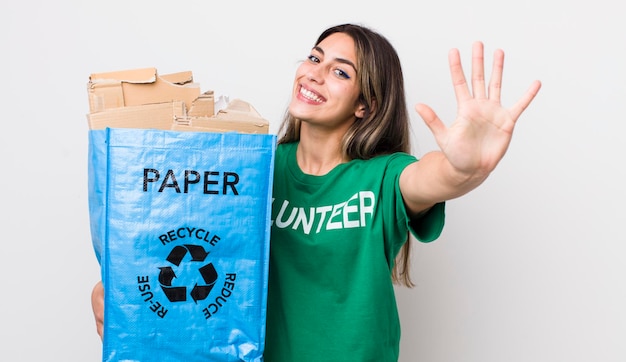 Bonita mujer hispana sonriendo y luciendo amigable mostrando el concepto de ecología número cinco