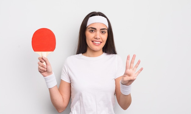 bonita mujer hispana sonriendo y luciendo amigable, mostrando el número cuatro. concepto de ping pong