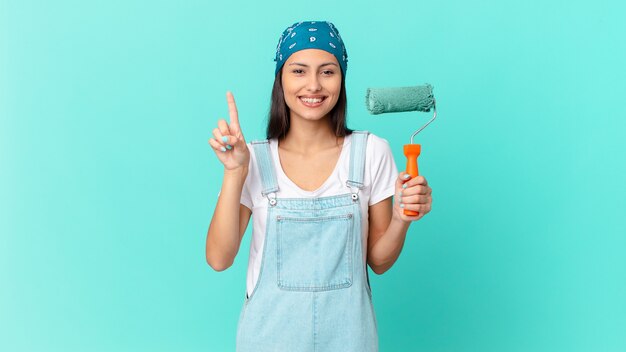 Bonita mujer hispana sonriendo y mirando amigable, mostrando el número uno. concepto de casa de pintura