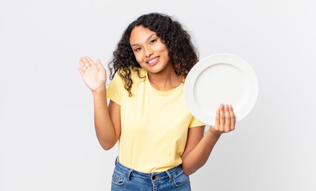 Bonita mujer hispana sosteniendo un plato limpio vacío