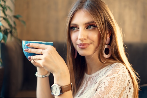 Bonita mujer joven disfrutando de una taza de café en una cafetería.