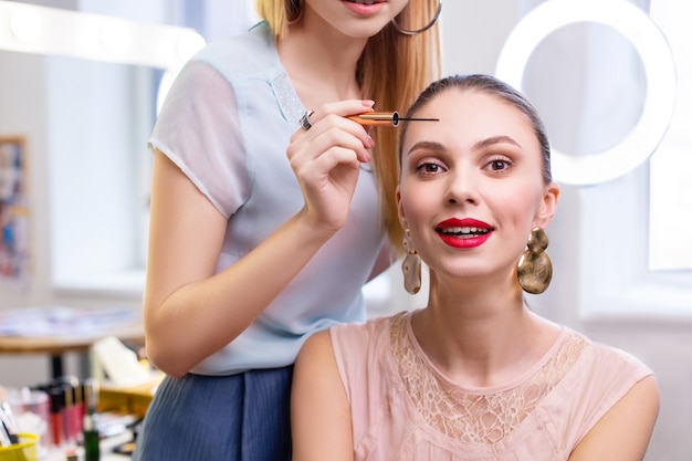 Bonita mujer joven con su pintor de ojos mientras está en el salón de belleza