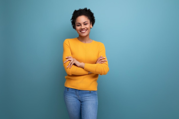 Bonita mujer latina con cabello afro en blusa amarilla casual posando en el fondo del estudio