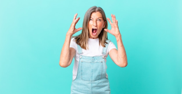 Bonita mujer de mediana edad gritando con las manos en el aire