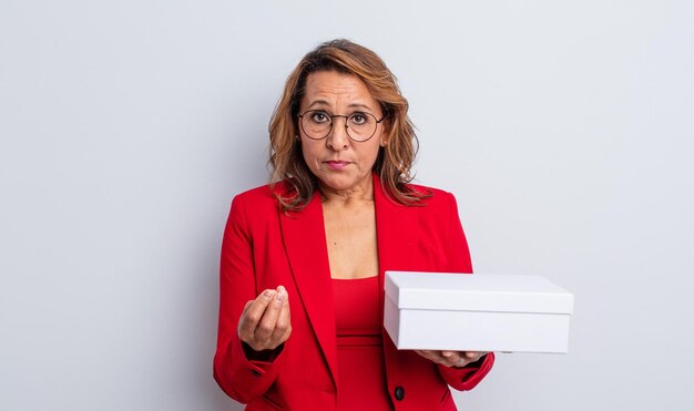 Bonita mujer de mediana edad haciendo capice o gesto de dinero, diciéndole que pague. paquete de caja blanca