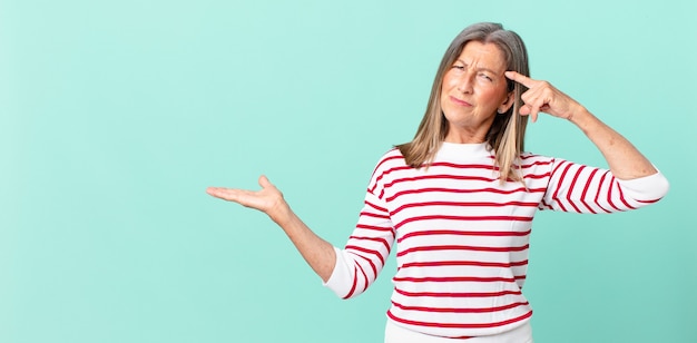 Bonita mujer de mediana edad que se siente confundida y perpleja, mostrando que estás loco