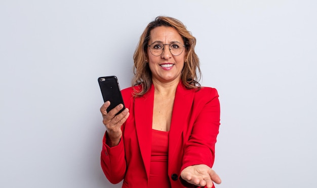 Bonita mujer de mediana edad sonriendo alegremente con amabilidad y ofreciendo y mostrando un concepto. concepto de negocio