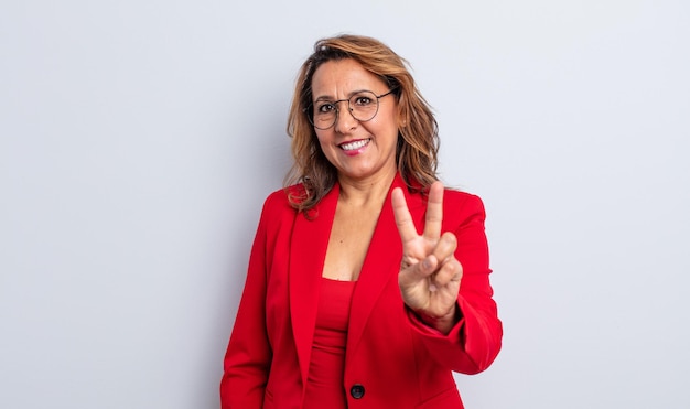 Bonita mujer de mediana edad sonriendo y luciendo feliz, gestando victoria o paz. concepto de empresaria