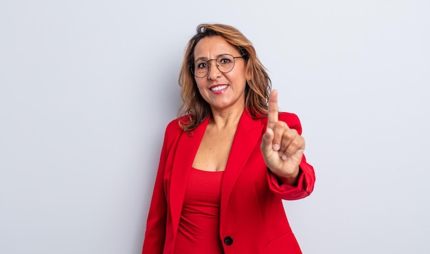 Bonita mujer de mediana edad sonriendo con orgullo y confianza haciendo el concepto de empresaria número uno