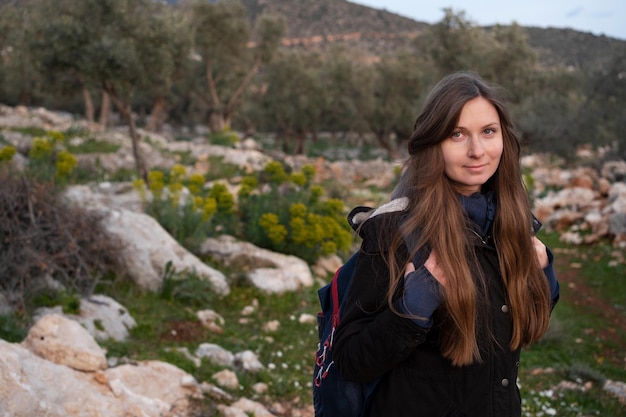 Bonita mujer morena de mediana edad con cabello largo con mochilasenderismotrekking en la naturalezamontaña verde