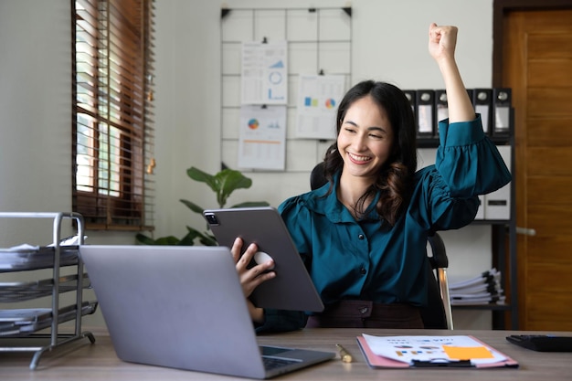 Bonita mujer de negocios asiática sentada en una laptop Y el trabajo salió con éxito y el objetivo se logró feliz y satisfecho con ella