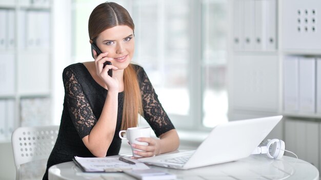 Bonita mujer de negocios sentada a la mesa con un portátil