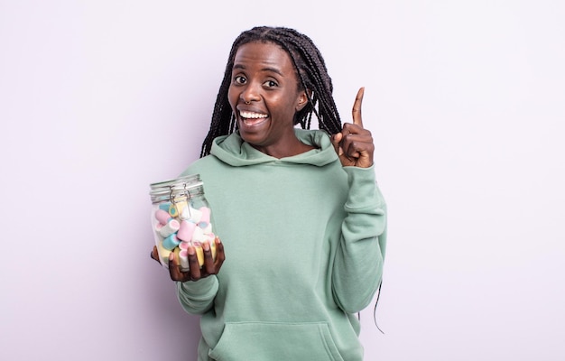 Bonita mujer negra que se siente como un genio feliz y emocionado después de darse cuenta de una idea. concepto de caramelos de gelatina