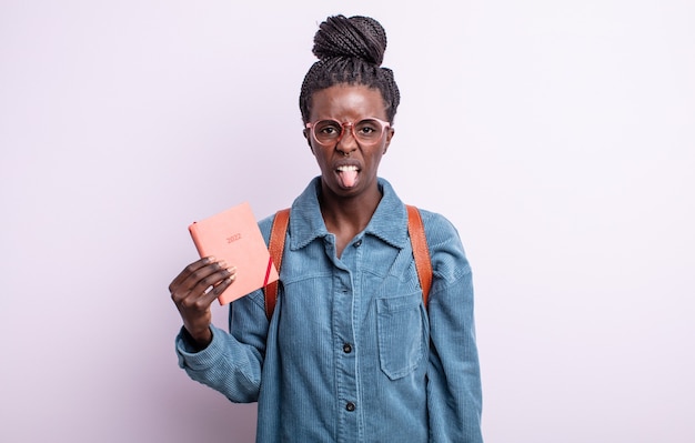 Bonita mujer negra que se siente disgustada e irritada y con la lengua fuera. concepto de agenda