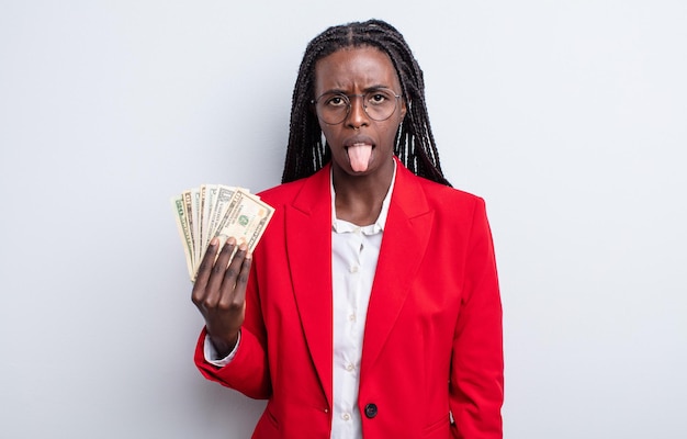 Bonita mujer negra que se siente disgustada e irritada y saca la lengua del concepto de billetes de dólar