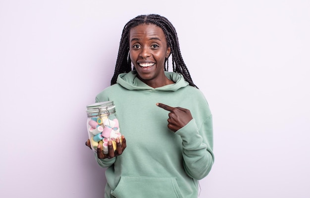 Bonita mujer negra que se siente feliz y apunta a sí misma con un entusiasmo. concepto de caramelos de gelatina