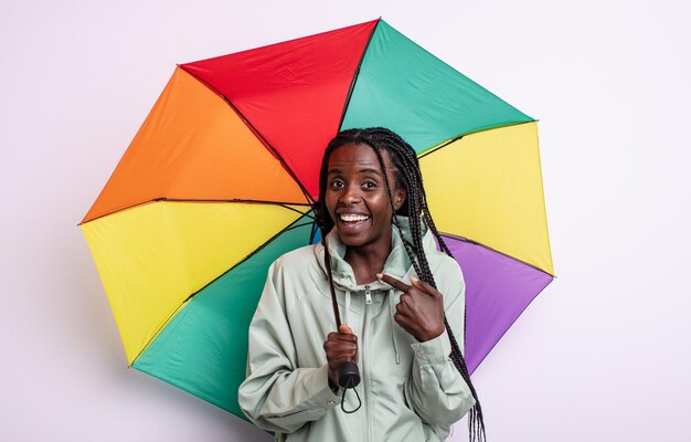 Bonita mujer negra que se siente feliz y apunta a sí misma con un entusiasmo. concepto de paraguas