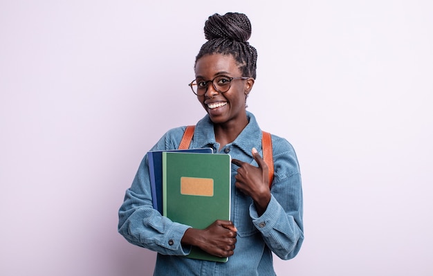 Bonita mujer negra que se siente feliz y apunta a sí misma con un entusiasmo. estudiante con concepto de libros