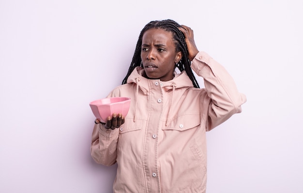 Bonita mujer negra sonriendo felizmente y soñando despierto o dudando. concepto de cuenco vacío