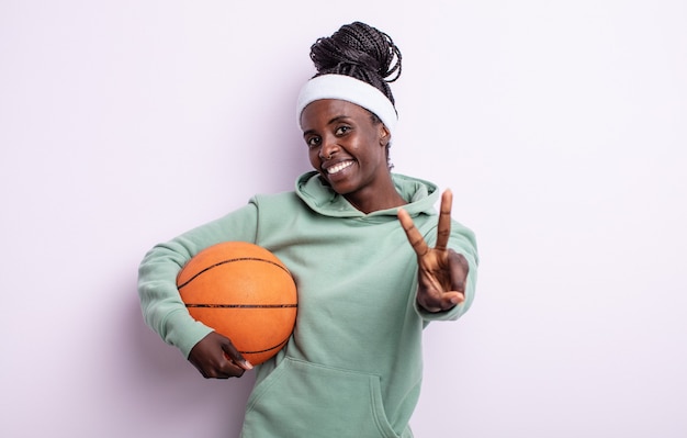 Bonita mujer negra sonriendo y mirando feliz, gesticulando victoria o paz. concepto de baloncesto