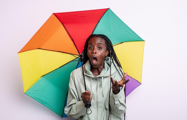 bonita mujer negra sorprendida, conmocionada y asombrada con una sorpresa increíble. concepto de paraguas