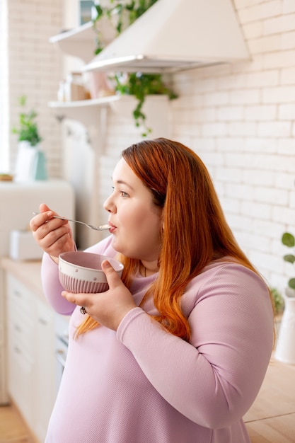 Bonita mujer pelirroja comiendo mientras desayuna por la mañana