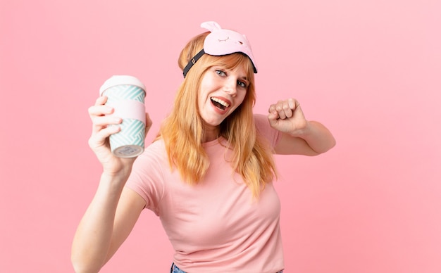 Bonita mujer pelirroja en pijama y tomando un café