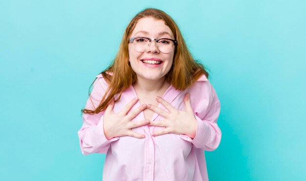 Bonita mujer pelirroja que parece feliz sorprendida orgullosa y emocionada apuntándose a sí misma