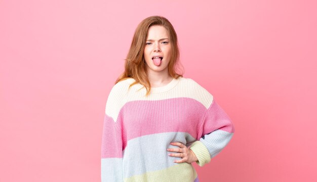 Foto bonita mujer pelirroja que se siente asqueada e irritada y saca la lengua