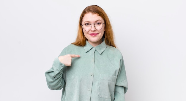 Bonita mujer pelirroja que se ve orgullosa, confiada y feliz sonriendo y apuntándose a sí misma o haciendo el signo número uno