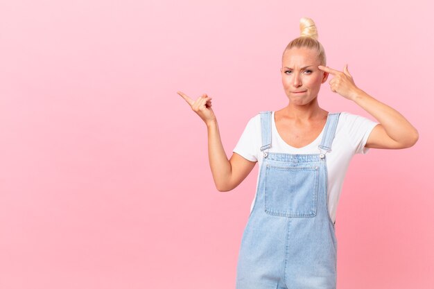 Bonita mujer rubia que se siente confundida y perpleja, mostrando que estás loco