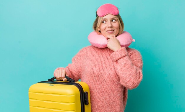 Bonita mujer rubia sonriendo con una feliz expresión de confianza con la mano en la barbilla concepto de pasajero de vuelo