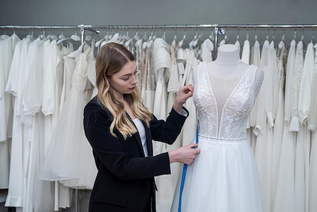 Bonita mujer sastre use cinta métrica para medir el vestido de novia en maniquí