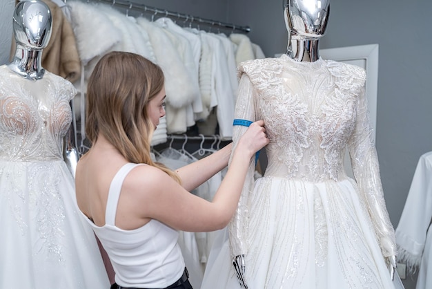 Bonita mujer sastre use cinta métrica para medir el vestido de novia en maniquí